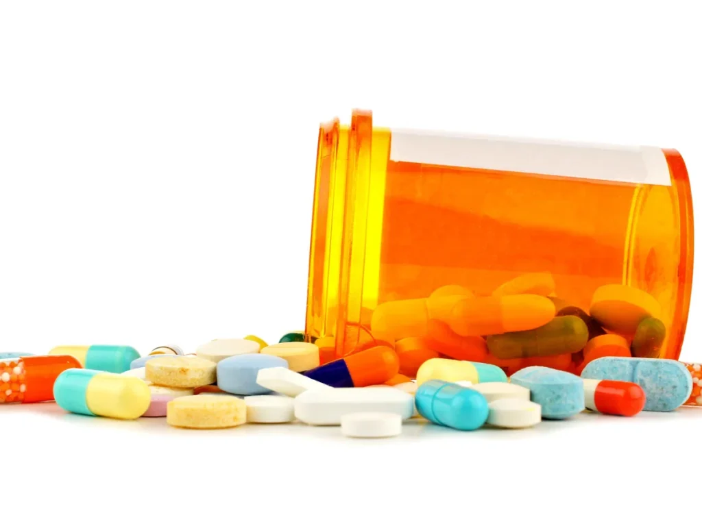 Various pet medicines and pills spilled from an orange prescription bottle.